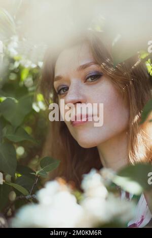 Close up woman with bright makeup surrounded by white flowers portrait picture Stock Photo