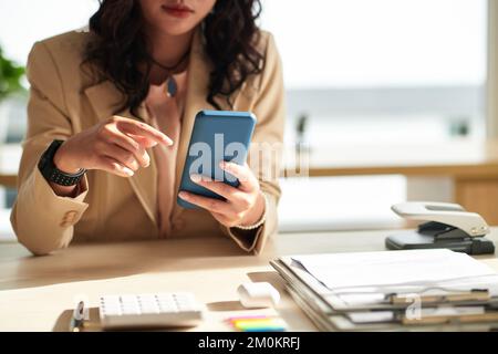 Businesswoman checking text messages and notifications on smartphone Stock Photo