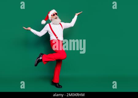 Full length photo of funky impressed senior guy wear x-mas costume walking empty space isolated green color background Stock Photo