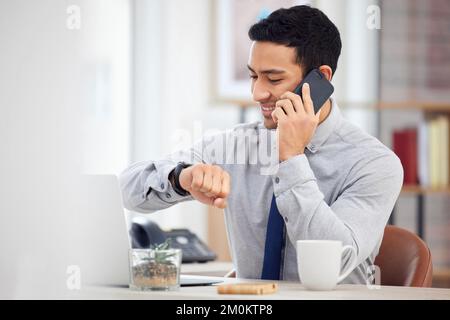 Mixed race businessman on a call using a phone and checking the time on his watch while sitting in an office at work. Hispanic male businessperson Stock Photo