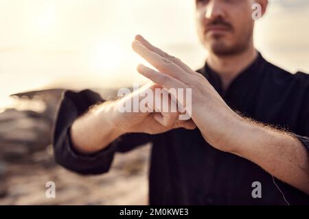 Karate, welcome or hands of zen man with peaceful, calm or mindfulness in nature at a beach for meditation. Fitness, sunset or martial arts teacher Stock Photo