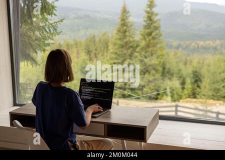 Woman works on laptop remotely in house on nature Stock Photo