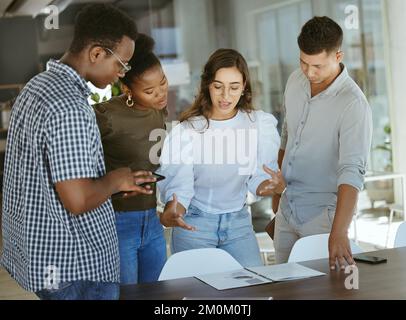 Group of focused businesspeople standing and talking together in an office. Hispanic businesswoman doing a presentation on a report to her colleagues Stock Photo