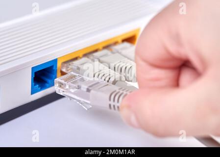 The hand inserts the Internet cable into the router. Stock Photo