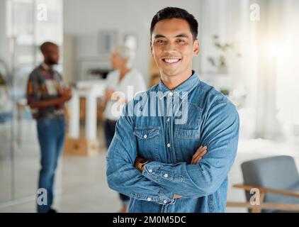 Portrait of a happy asian businessman standing with his arms crossed at work. One confident chinese male manager standing in an office at work. One Stock Photo