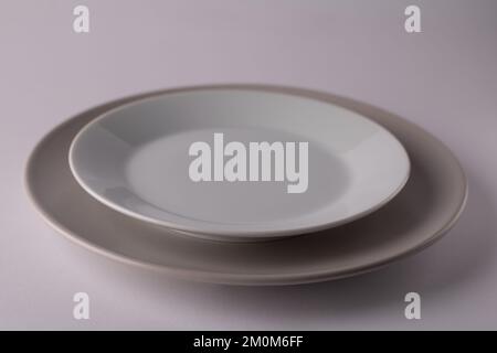photo of two light-coloured plates standing on top of each other on a white background Stock Photo