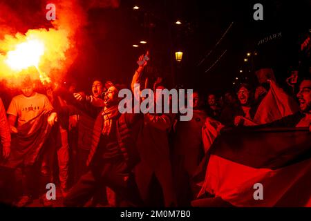 Barcelona, Spain. 06th Dec, 2022. Supporters of the Moroccan soccer team celebrate their victory over Spain in the Qatar 2022 World Cup with lit red flares on La Rambla in Barcelona. The Moroccan community residing in Barcelona went out to celebrate their pass to the quarterfinals on the Ramblas of Barcelona after beating the Spanish team in the Qatar 2022 World Cup. Credit: SOPA Images Limited/Alamy Live News Stock Photo