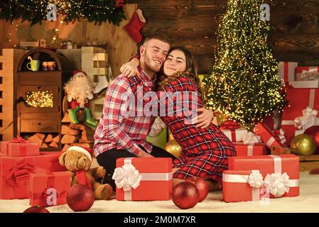 Christmas composition. evening before xmas. Enjoying spending time together in New Year Eve. Couple in love sitting next to Christmas tree. hugging Stock Photo