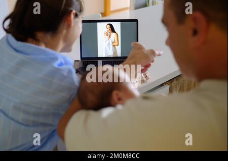Family watching photo of newborn and mother on laptop Stock Photo