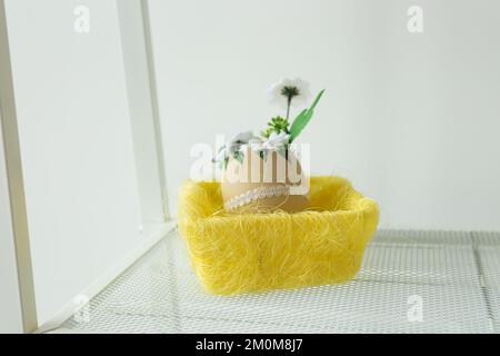Spring artificial flowers explosion popping out of cracked eggshell in easter basket. Creative Happy Easter and spring or summer, food greeting card Stock Photo