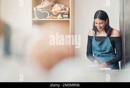 One happy young hispanic waitress working in a store or cafe. Friendly woman and coffeeshop owner managing a successful restaurant startup Stock Photo