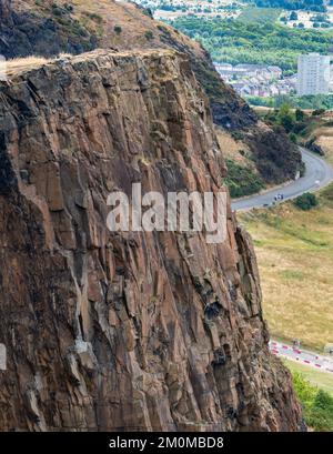 Looking down to pathways of Holyrood Park far below.narrow paths across sheer vertical cliff faces,dramatic views across the Scottish capital city,on Stock Photo