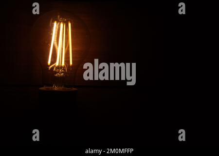 burning light bulb on wood surface and black background Stock Photo
