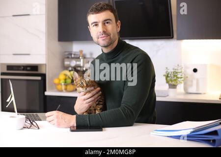 Attractive man working from home with his cat Stock Photo