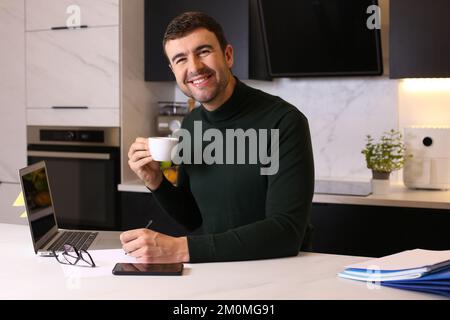 Man drinking a cup of coffee while working from home Stock Photo