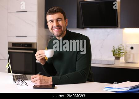 Man drinking a cup of coffee while working from home Stock Photo