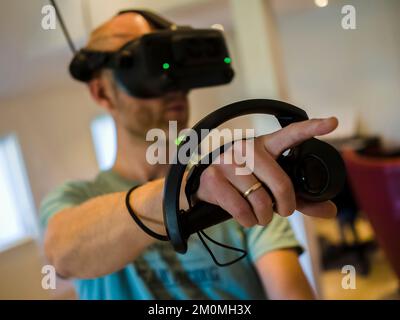 A closeup of the man with a VR headset holding a game controller. Stock Photo