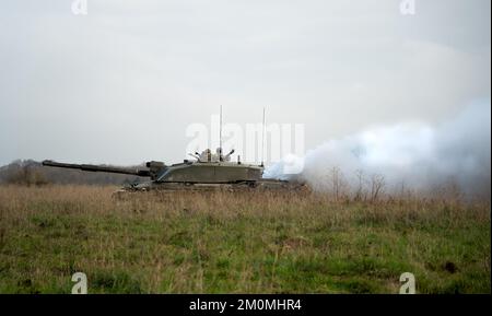 side profile close-up of commander and gunner directing action on a British army FV4034 Challenger 2 ii main battle tank, diesel smoke screen Stock Photo
