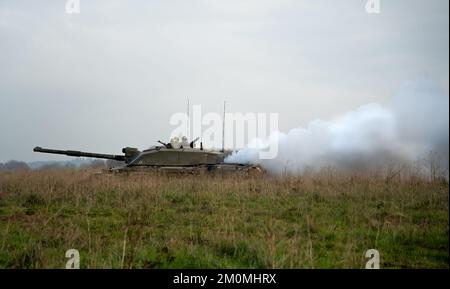 side profile close-up of commander and gunner directing action on a British army FV4034 Challenger 2 ii main battle tank, diesel smoke screen Stock Photo