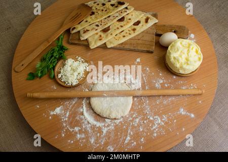 Curd cheese and parsley between butter dough, handmade Turkish traditional pastries 'gozleme', top view. Stock Photo