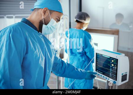 Doctor, hospital and medical machine with monitor screen during surgery for dialysis, healthcare and analysis in a room with a face mask and scrubs Stock Photo