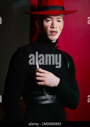 Portrait, fashion and stylish man with vitiligo posing on a red studio background looking confident. Confidence, face and trendy or edgy man with Stock Photo