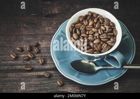 Roasted coffee beans in blue cup on wooden table Stock Photo
