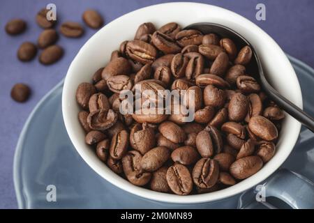 Close up of blue cup and saucer filled with organic arabica coffee beans Stock Photo