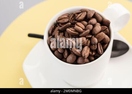 White cup full of roasted flavoursome whole coffee beans Stock Photo