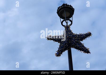 Unlit christmas lights star hanging on a street lamp Stock Photo
