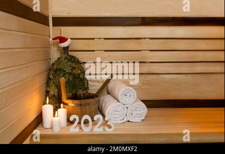 Sauna. 2023 white numbers, wooden bucket, candles, Santa hat on it Stock Photo