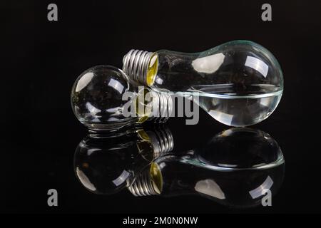 Two turned off light bulbs on black background with reflection. Stock Photo