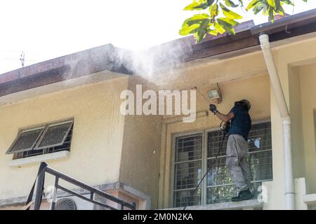 Worker using high pressure water jet spray gun to wash and clean dirt from roof ceiling Stock Photo