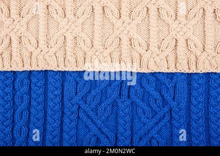 Knitted blue and beige background. Large knitted fabric with a pattern. Close-up of a knitted blanket. Stock Photo