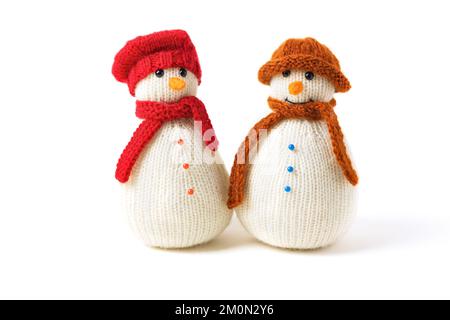 Two knitted snowmen on a white background in red and brown hats. Merry Christmas and New Year 2023 greeting card Stock Photo