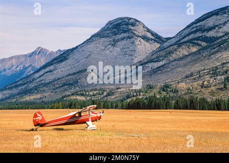 Propeller plane on a grass runway by the mountains Stock Photo