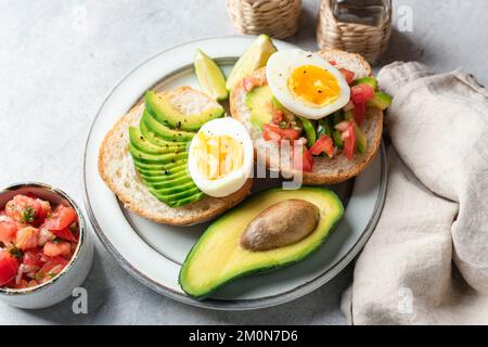 Healthy breakfast with avocado, egg, tomatoes and toasted bread on a plate Stock Photo