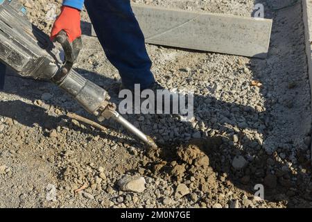 Concrete surface of road was dug and drilled by construction road workers using jackhammer Stock Photo