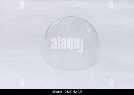 glass ball or transparent bauble on white snow. winter outdoors. brilliant sphere snowy background. Stock Photo