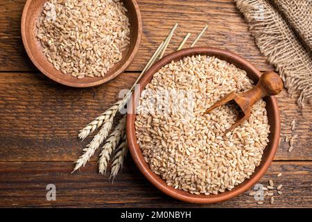Wheat grains in bowl on a wooden background. Agriculture, harvest, bread baking concept Stock Photo