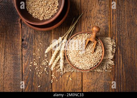 Wheat grains in bowl on a wooden table background. Concept of harvesting, agriculture, baking bread Stock Photo