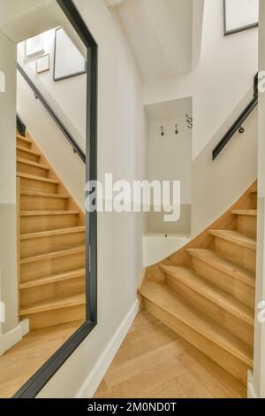 Interior of narrow corridor with radiator hanging on wall against stairway in daylight Stock Photo