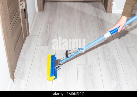 Cleaning the house. A woman washes a laminate floor in the hallway with a mop. Stock Photo