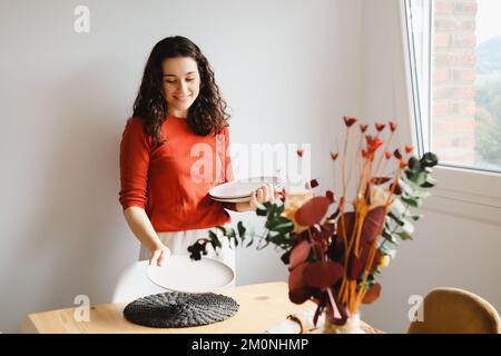 Young happy woman setting the table for dinner at home Stock Photo
