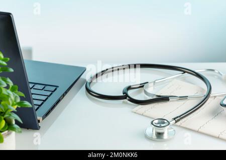 Doctor's office desk with laptop, medical documents, cardiogram, tonometer and stethoscope on a blue background. Medicine, medication treatment and me Stock Photo