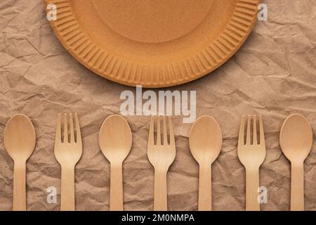 Wooden forks and spoons and paper plate on crumpled paper Stock Photo