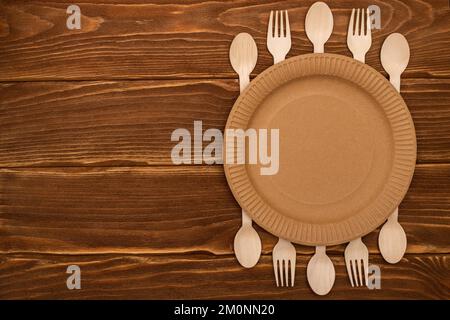 Wooden forks and spoons and paper plate on wooden background Stock Photo