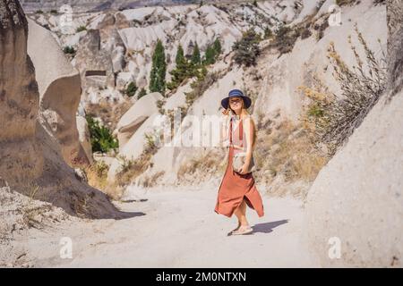 Young woman exploring valley with rock formations and fairy caves near Goreme in Cappadocia Turkey Stock Photo