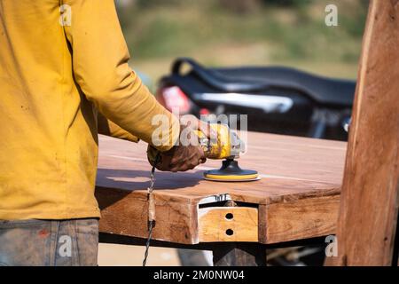 slow motion shot of carpenter using a rotary sanding machine to clean and polish wooden table as a hobby or occupation to sell in banjara market Stock Photo