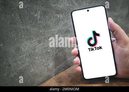 Tik tok application logo on smartphone screen in hand, concrete background with copy space for text. Tiktok social media app icon. Krakow, Poland - November 11, 2022. Stock Photo